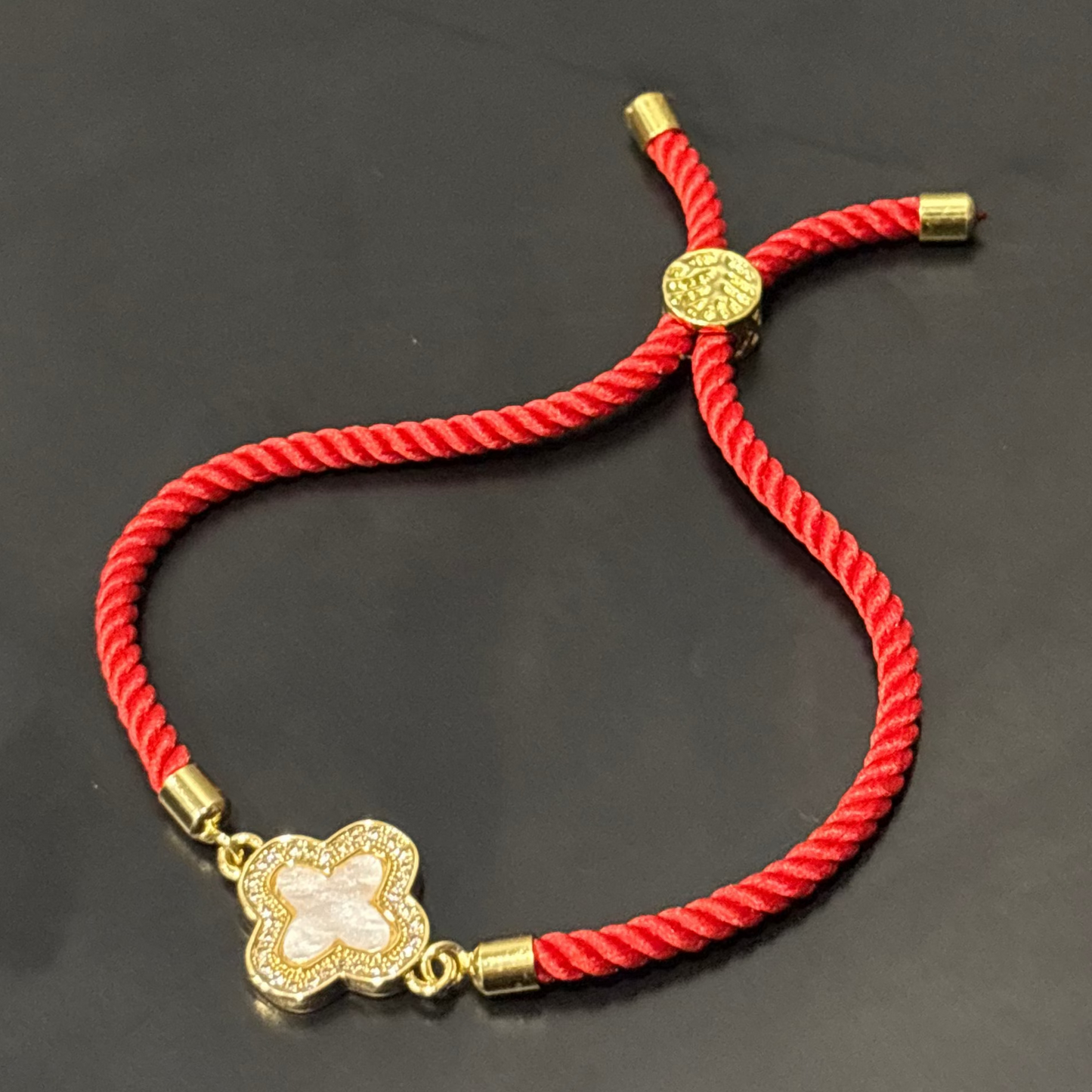 Red bracelet with a gold clasp on a dark surface