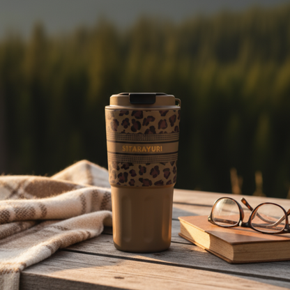 Tumbler with leopard print design on a wooden table with a scenic background of mountains and trees.